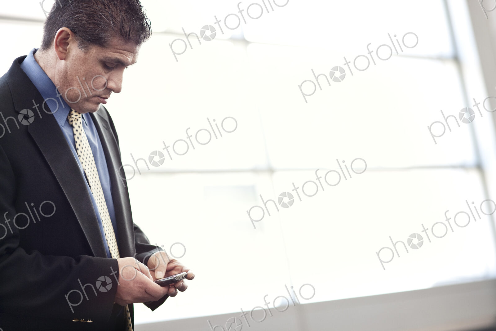 HIspanic businessman checking his cell phone in a conference centre lobby.