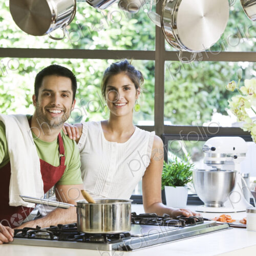 HIspanic couple at home in their kitchen cooking together. HIspanic couple at home in their kitchen cooking together.
