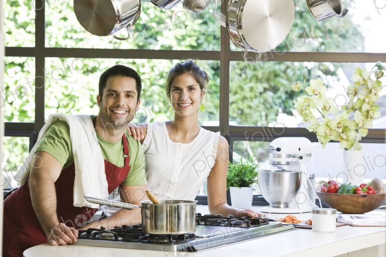 HIspanic couple at home in their kitchen cooking together.