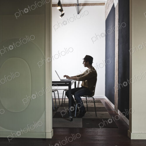 HIspanic male working on a laptop computer in a small conference room. HIspanic male working on a laptop computer in a small conference room.