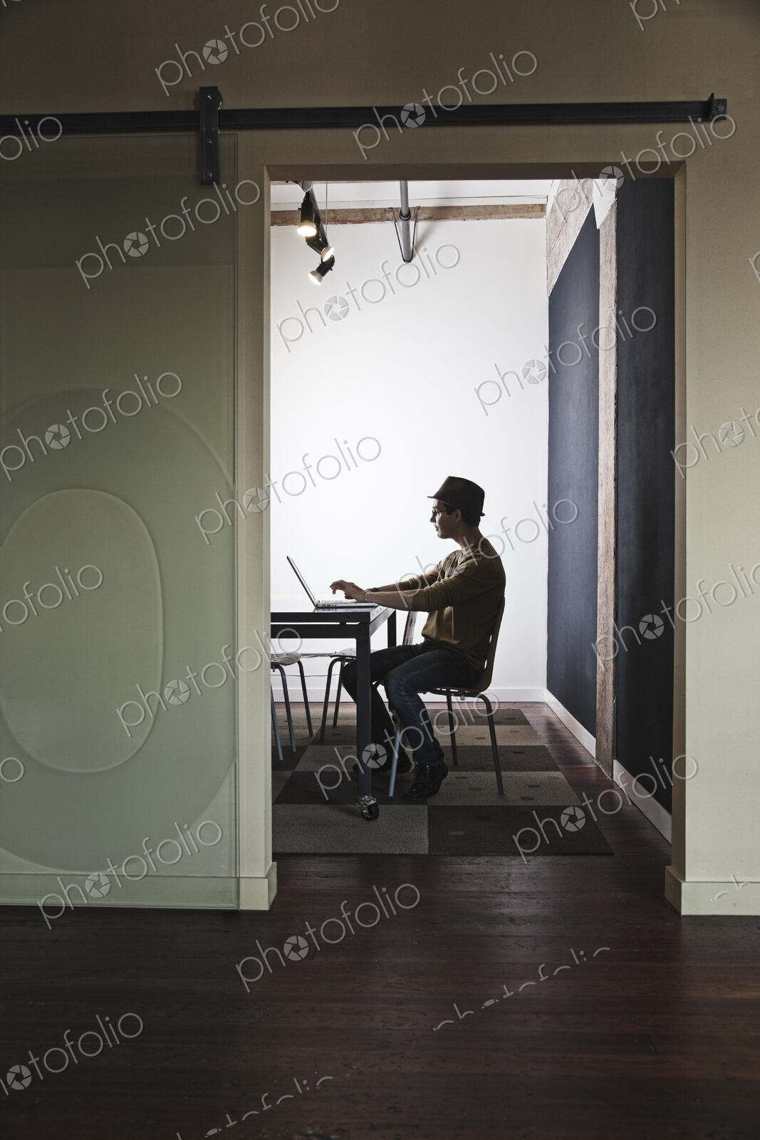 HIspanic male working on a laptop computer in a small conference room.