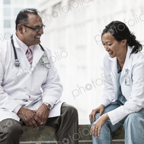 HIspanic man and asian woman doctors conferring over a case in a hospital. HIspanic man and asian woman doctors conferring over a case in a hospital.