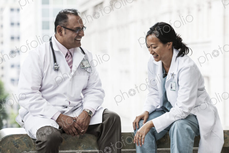 HIspanic man and asian woman doctors conferring over a case in a hospital.