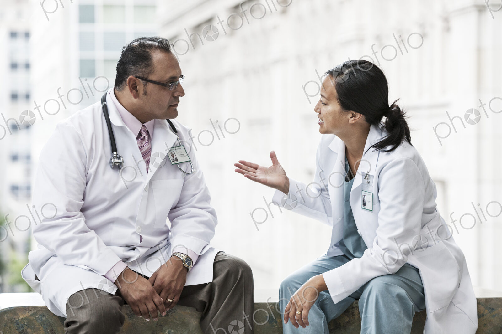 HIspanic man and asian woman doctors conferring over a case in a hospital.