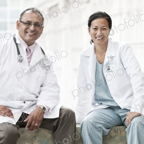 HIspanic man and asian woman doctors conferring over a case in a hospital. HIspanic man and asian woman doctors conferring over a case in a hospital.