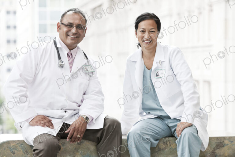 HIspanic man and asian woman doctors conferring over a case in a hospital.