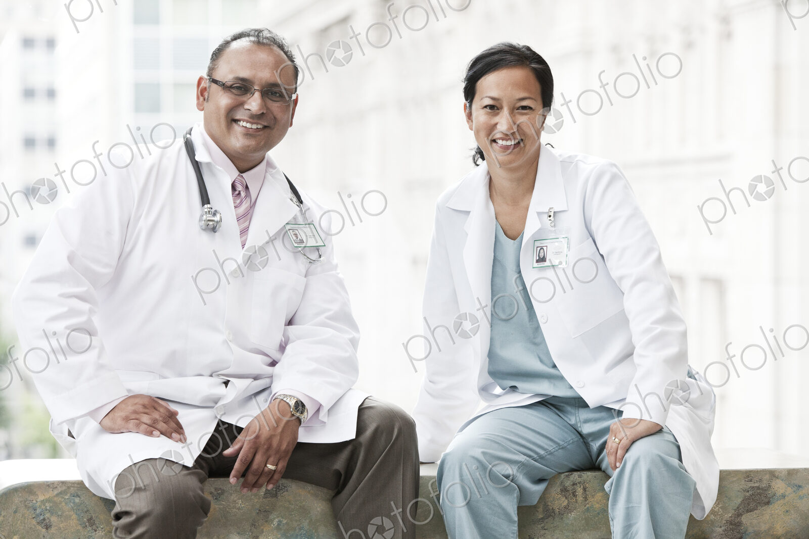 HIspanic man and asian woman doctors conferring over a case in a hospital.
