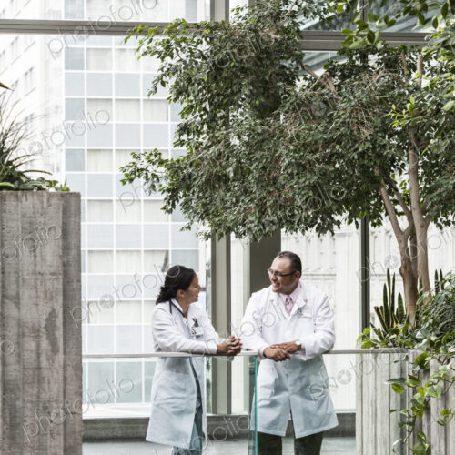 HIspanic man and asian woman doctors conferring over a case in a hospital. HIspanic man and asian woman doctors conferring over a case in a hospital.