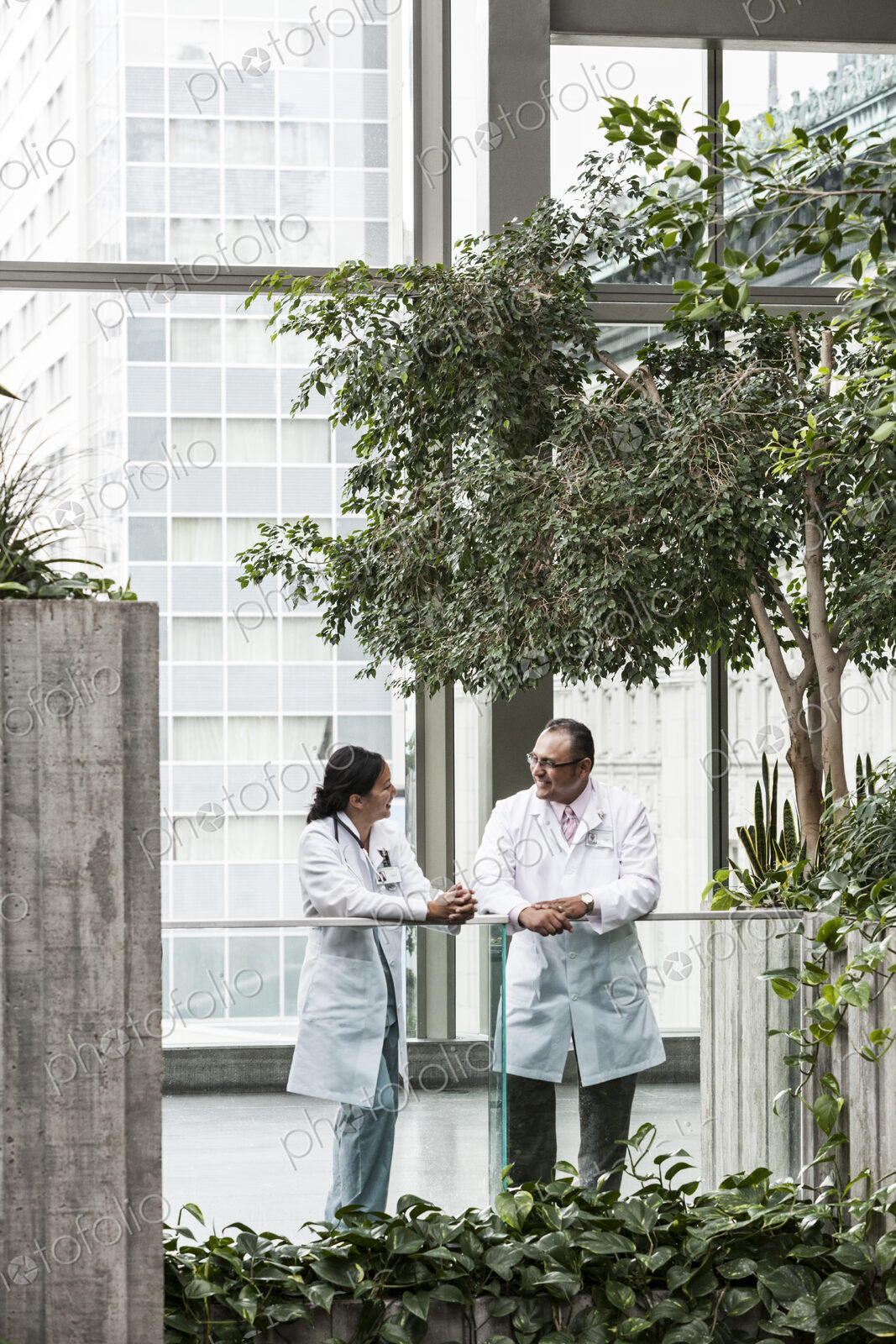 HIspanic man and asian woman doctors conferring over a case in a hospital.