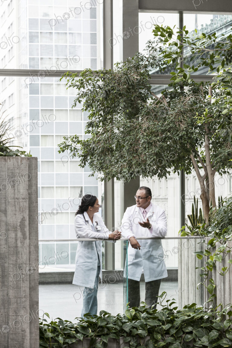 HIspanic man and asian woman doctors conferring over a case in a hospital.