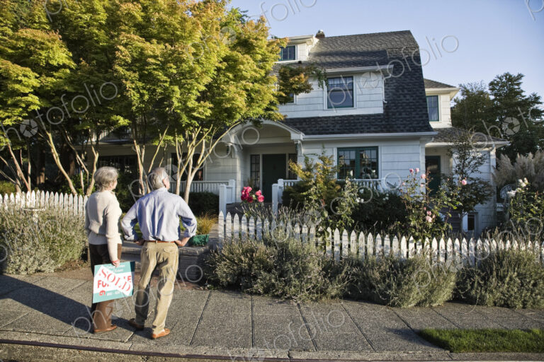 HIspanic seniors in front of their newly puchased remodeled older style home.
