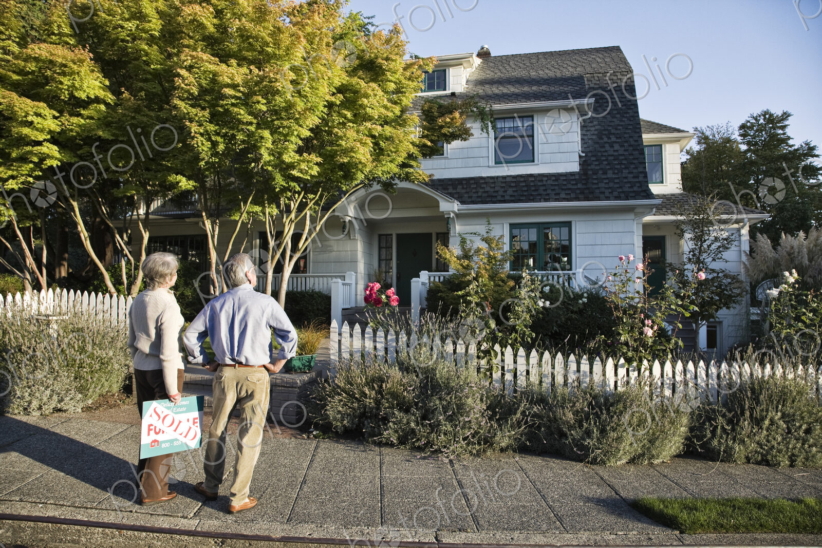 HIspanic seniors in front of their newly puchased remodeled older style home.
