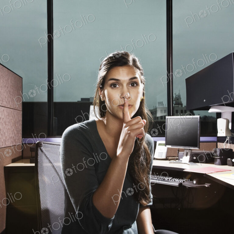 HIspanic woman asking for quiet in an office cublicle.