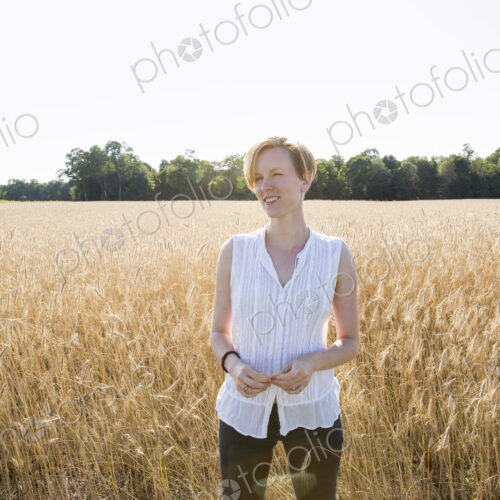 Half length portrait of a young woman standing in a cornfield.