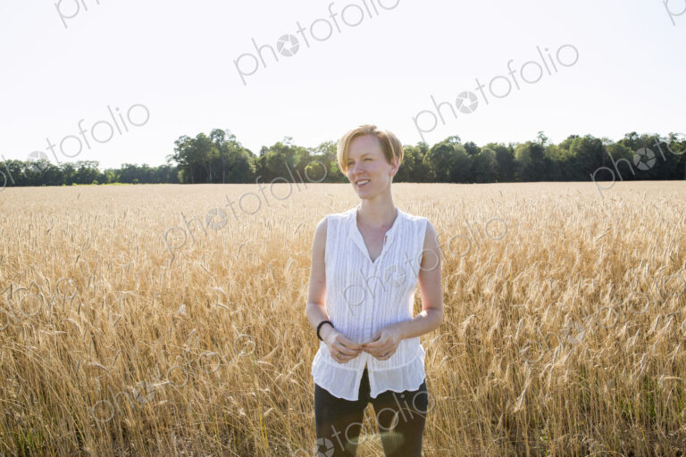 Half length portrait of a young woman standing in a cornfield.