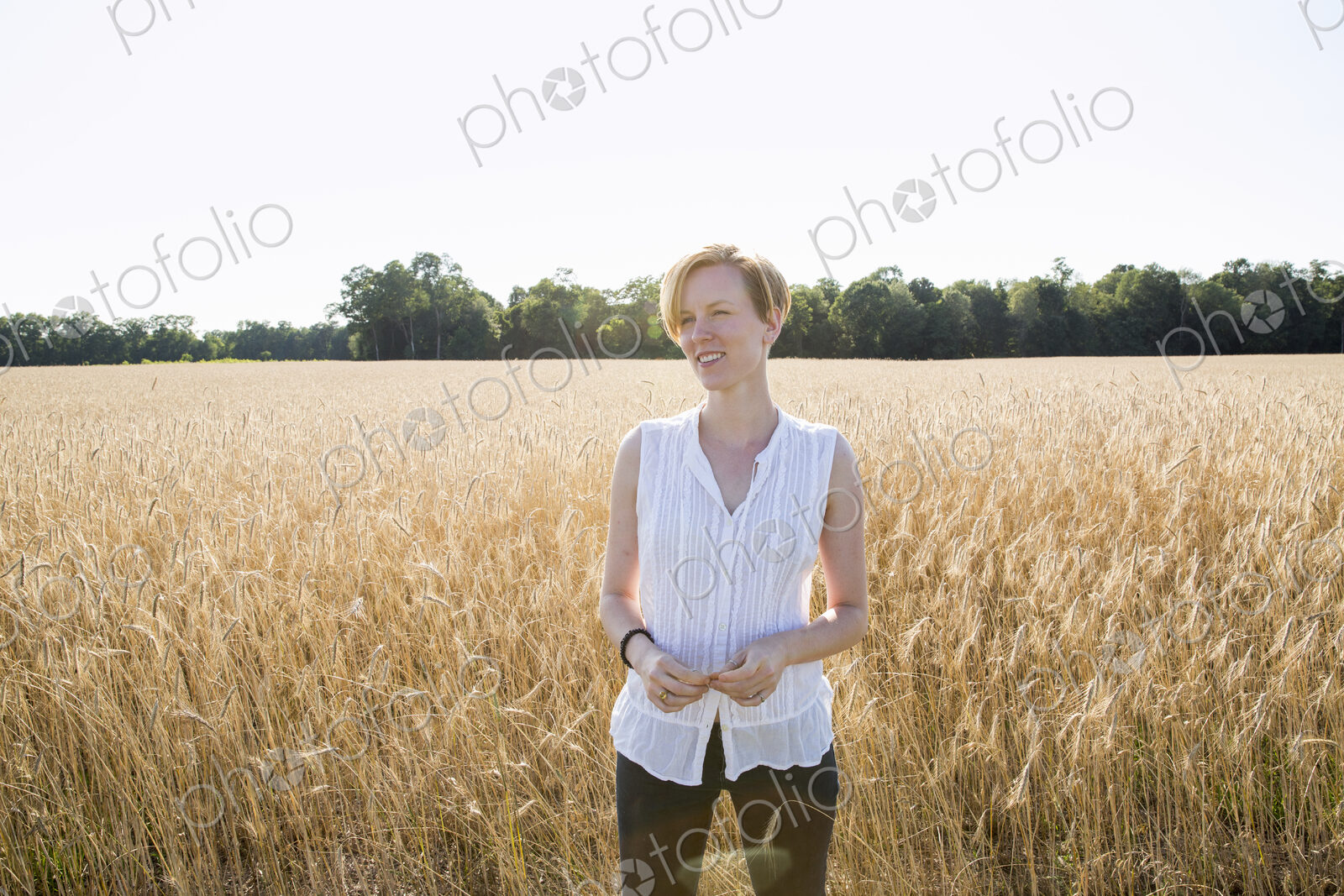 Half length portrait of a young woman standing in a cornfield.