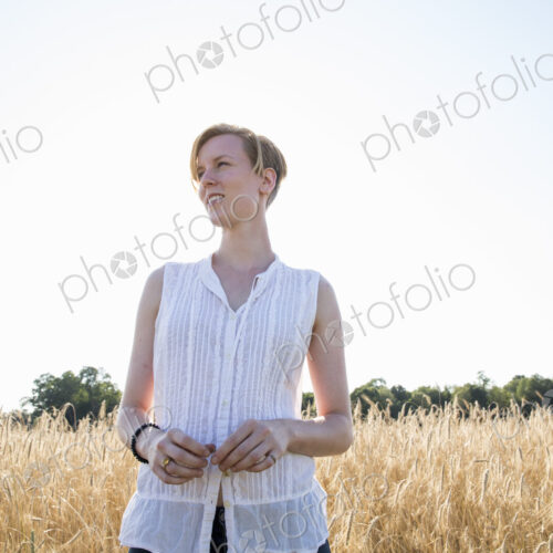 Half length portrait of a young woman standing in a cornfield.