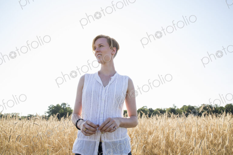 Half length portrait of a young woman standing in a cornfield.