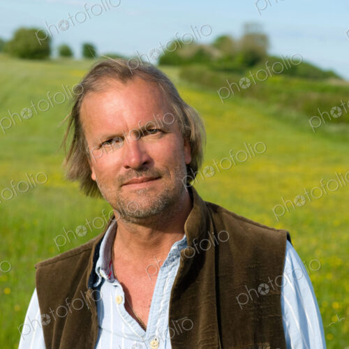Half length portrait of mature man standing outdoors on a meadow, smiling at camera. Half length portrait of mature man standing outdoors on a meadow, smiling at camera.