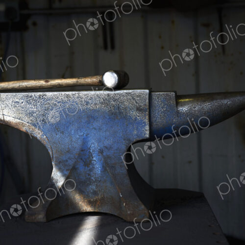 Hammer lying on an iron anvil in a traditional blacksmith's forge.