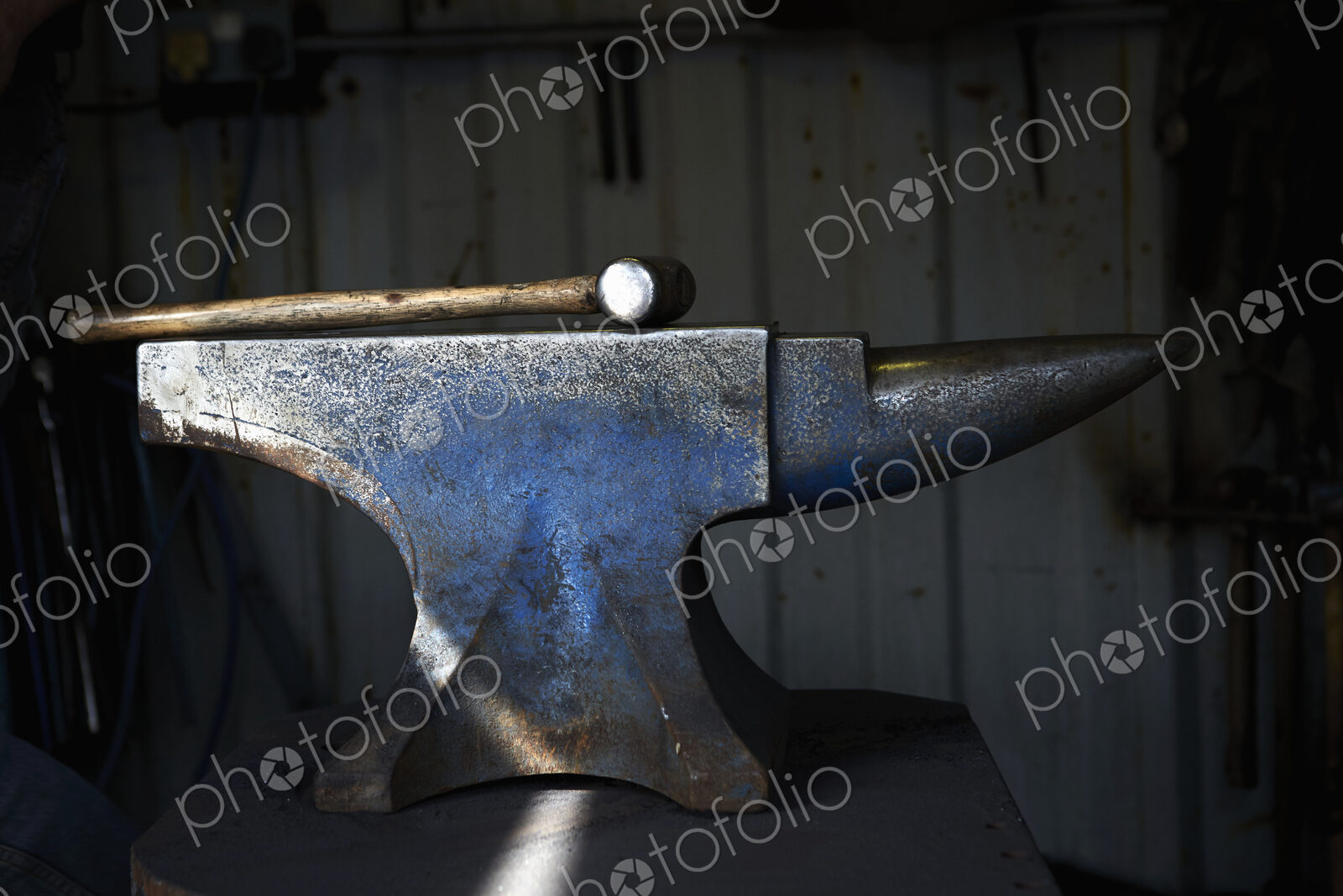 Hammer lying on an iron anvil in a traditional blacksmith’s forge.
