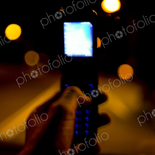 Hand holding flip phone at night Hand holding flip phone at night