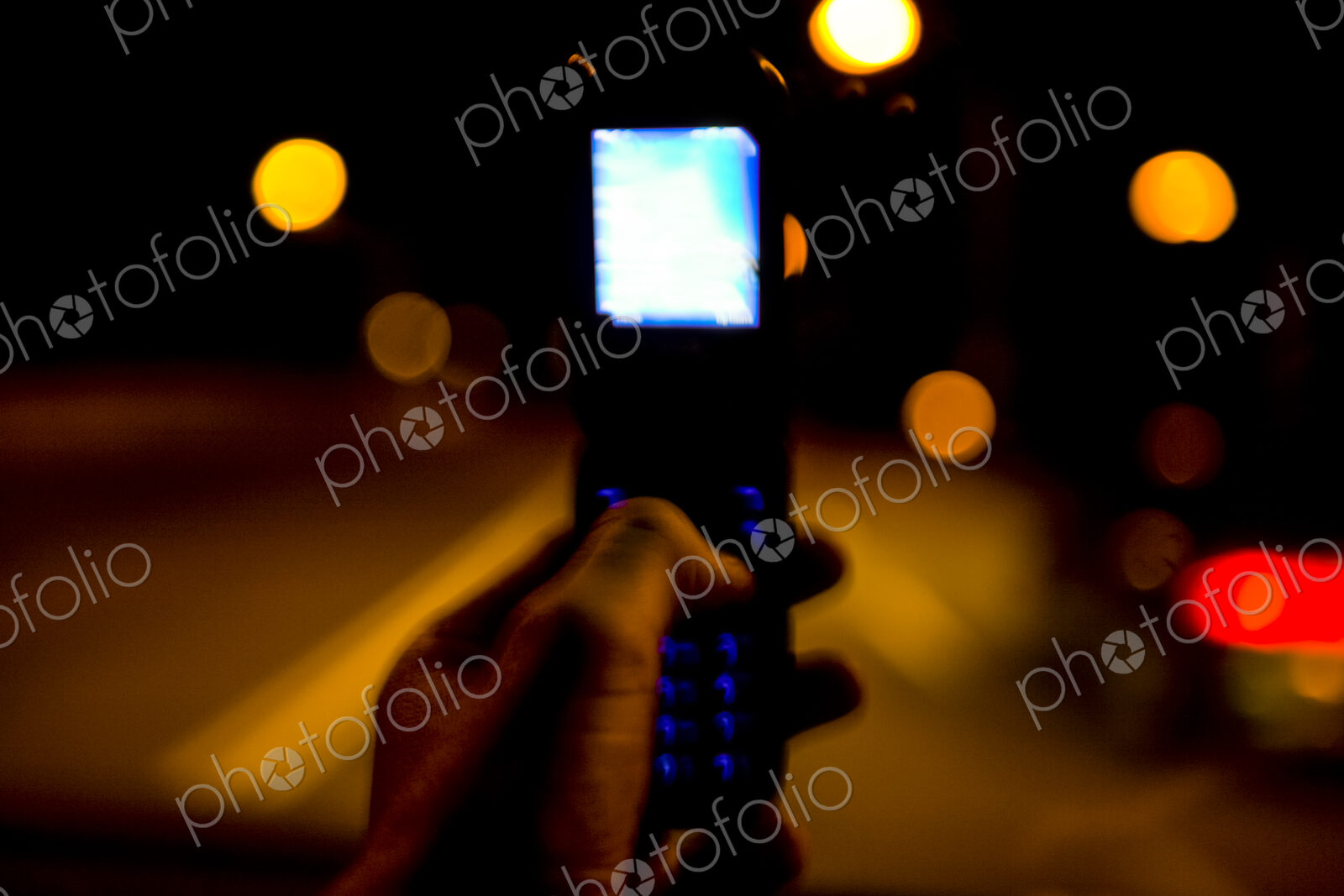 Hand holding flip phone at night