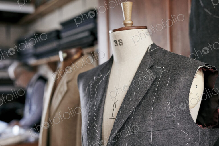 Handmade suit with stiching visible hanging on mannequin