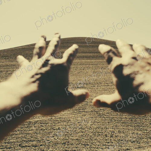 Hands extending reaching out towards ploughed farmland, near Pullman, Washington, USA Hands extending reaching out towards ploughed farmland, near Pullman, Washington, USA