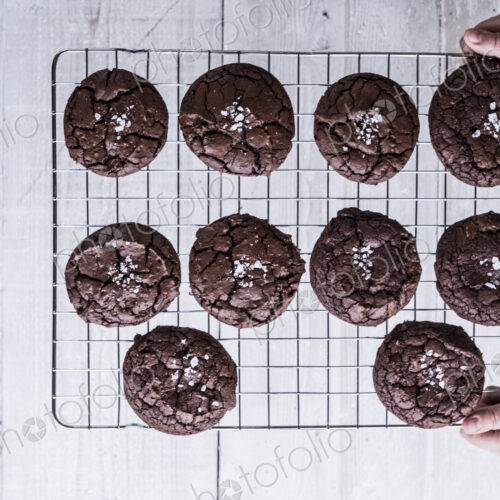 Hands holding a wire cooling rack of baked chocolate brownies.