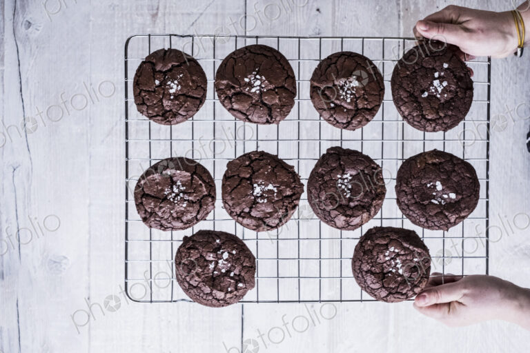 Hands holding a wire cooling rack of baked chocolate brownies.