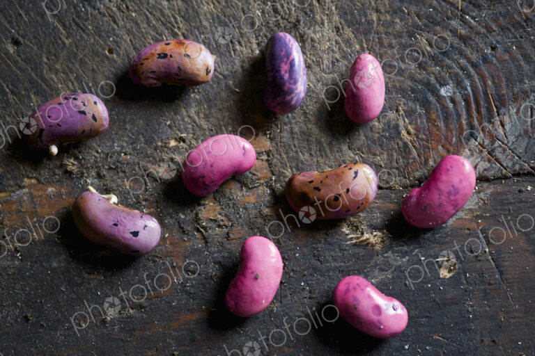 Harvested runner bean seeds, spaced out on a wooden surface, drying over winter.