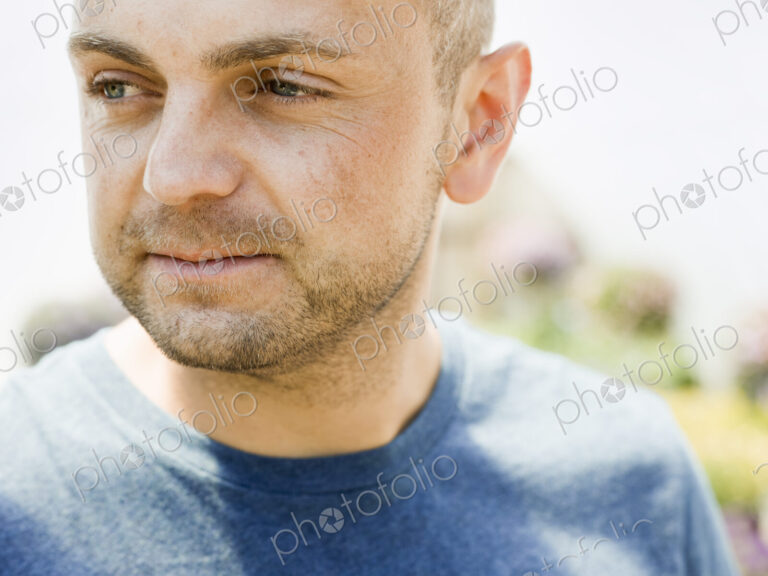 Head and shoulders portrait of a man with stubble in a blue teesirt.