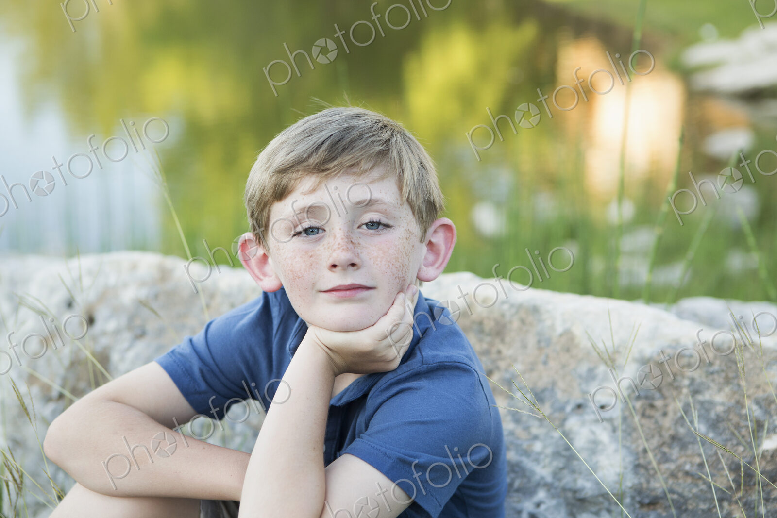 Head and shoulders portrait of a young boy sitting with his chin resting on his hand.