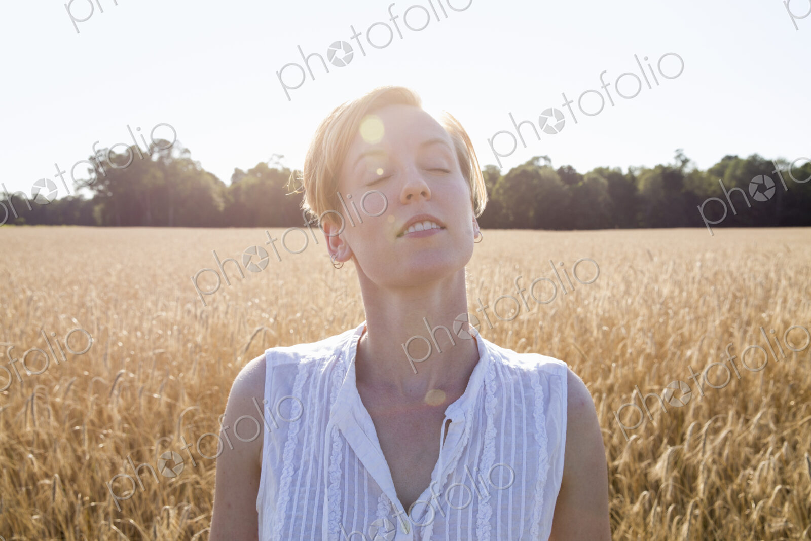 Head and shoulders portrait of a young woman standing in a cornfield.