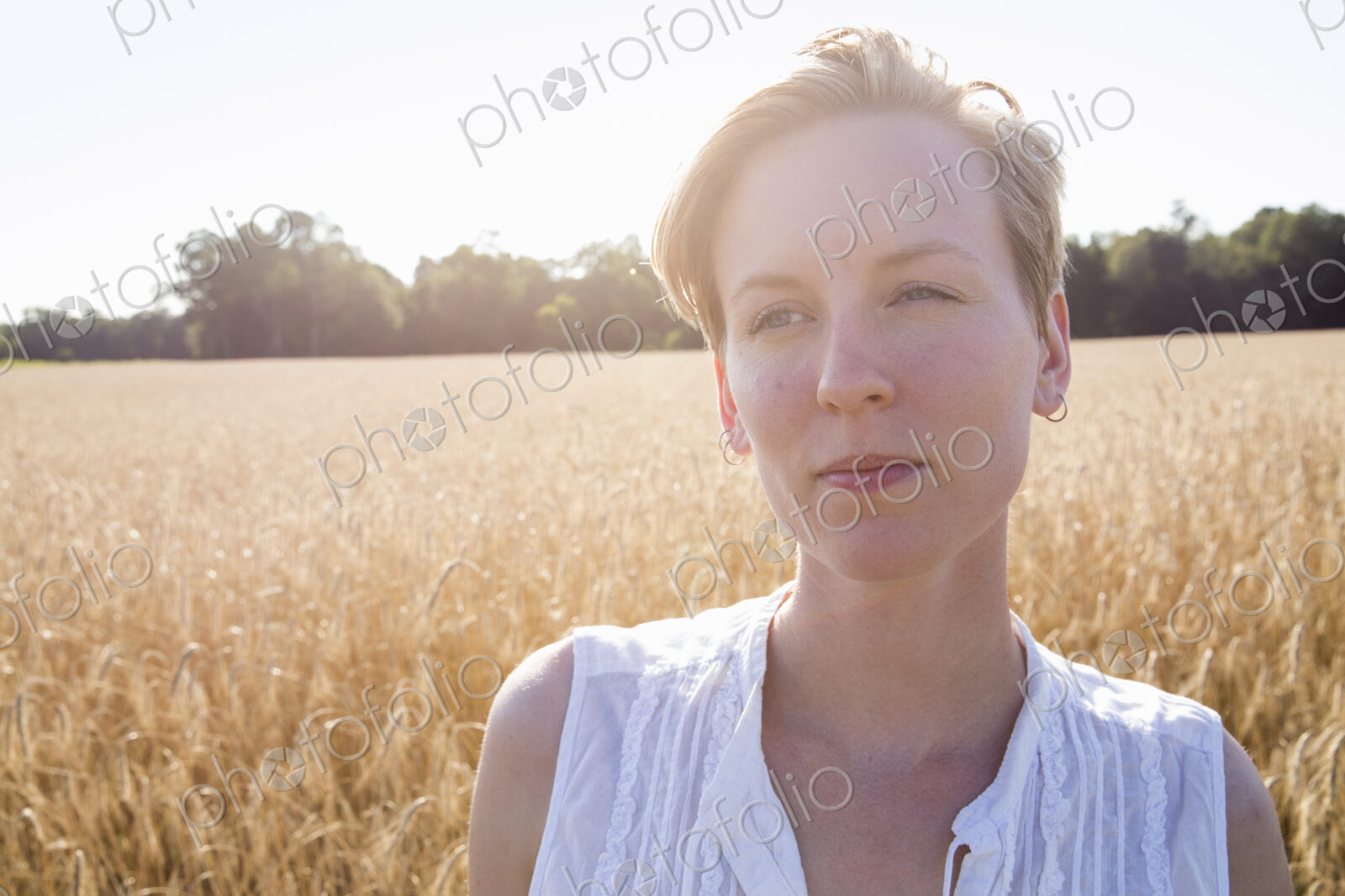 Head and shoulders portrait of a young woman standing in a cornfield.