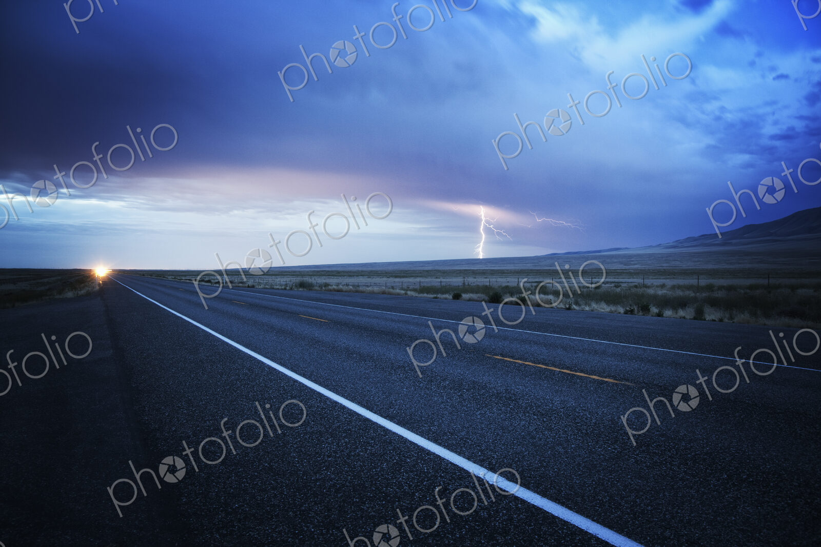 Headlights of a commercial truck on a highway late in the day.