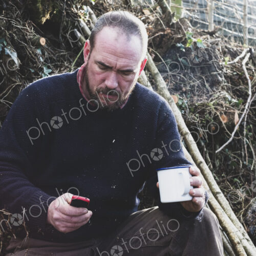 Hedge layer on a tea break checking his mobile phone.