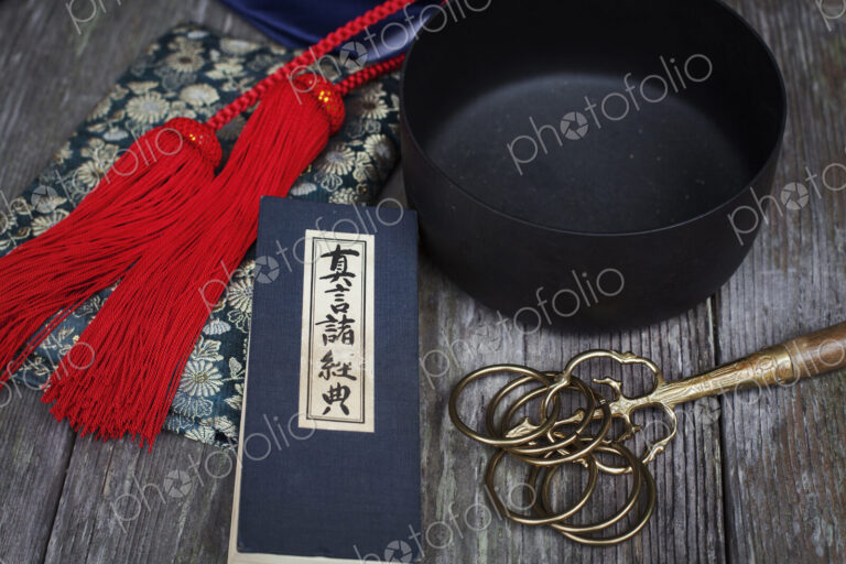 High angle close up of Buddhist prayer text, red silk tassel of a mala and black…
