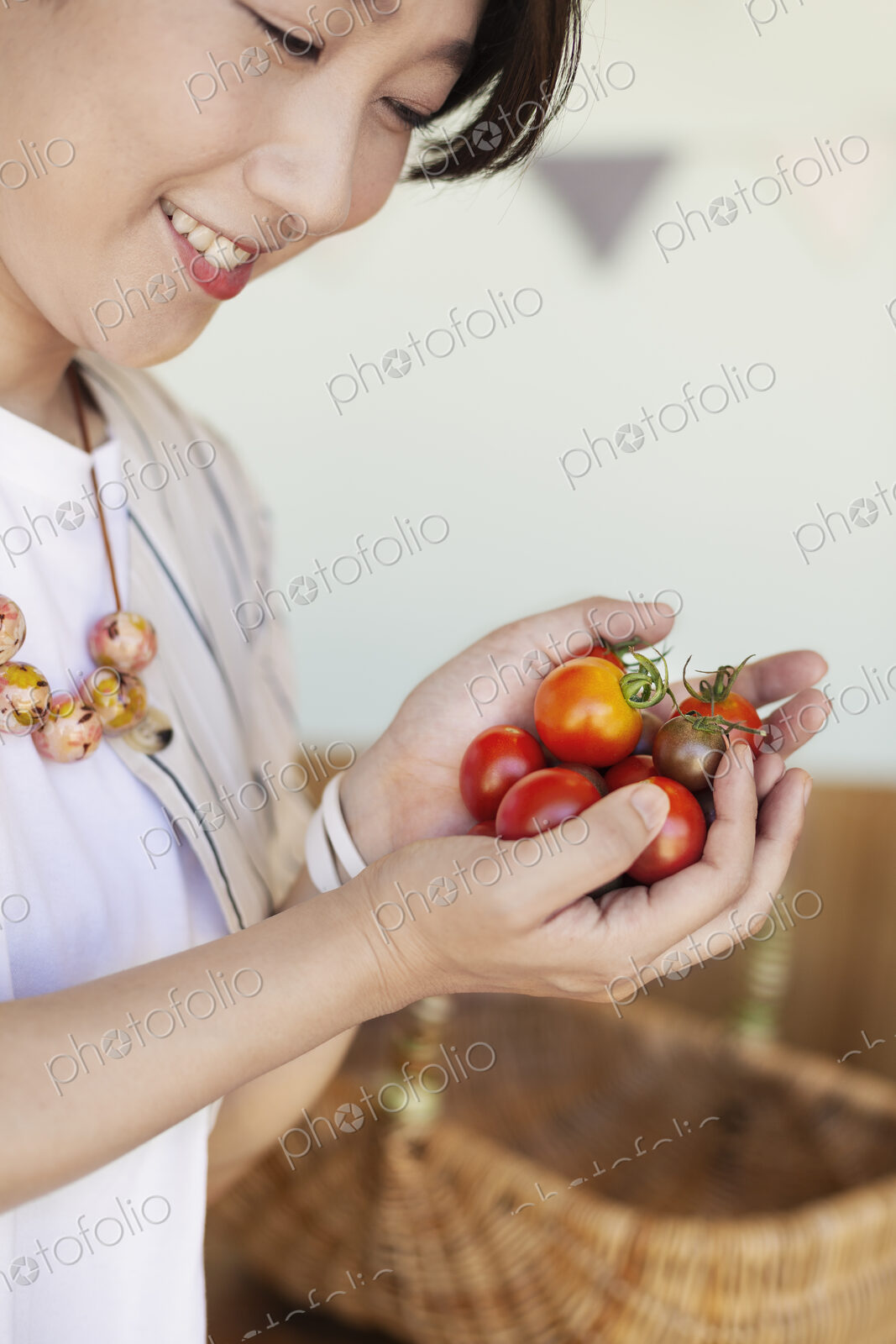 High angle close up of Japanese woman holding freshly picked tomatoes.
