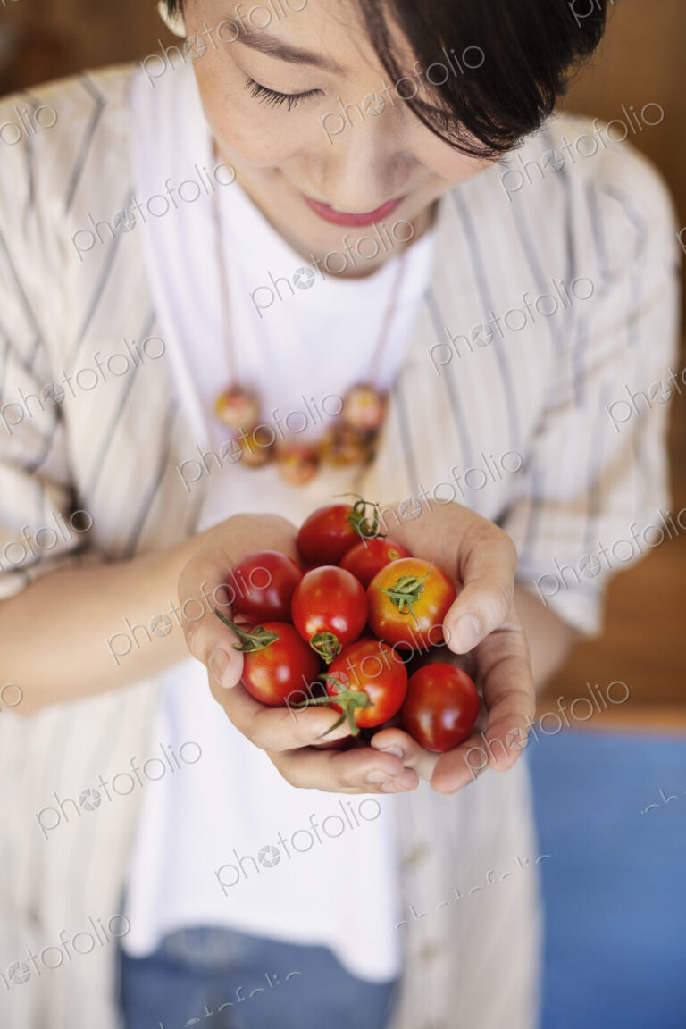 High angle close up of Japanese woman holding freshly picked tomatoes.