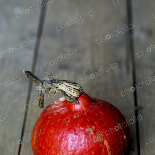 High angle close up of a Red Kuri pumpkin on rustic wooden table.
