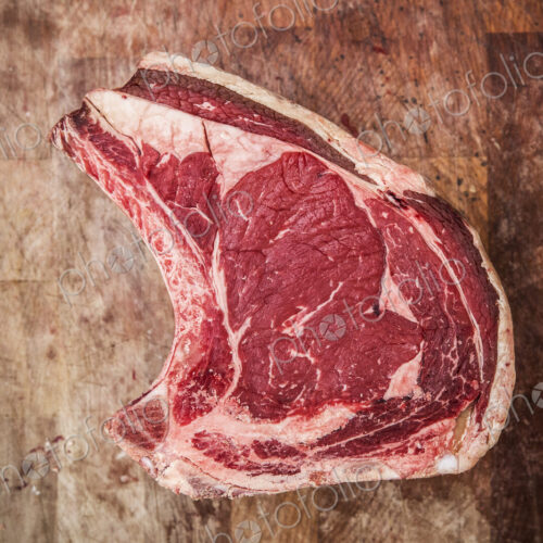 High angle close up of a beef forerib on a wooden butcher's block.