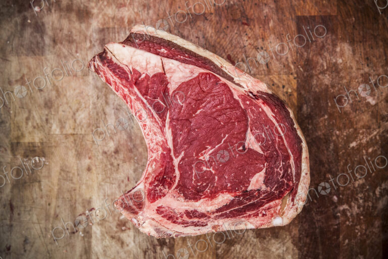High angle close up of a beef forerib on a wooden butcher's block.