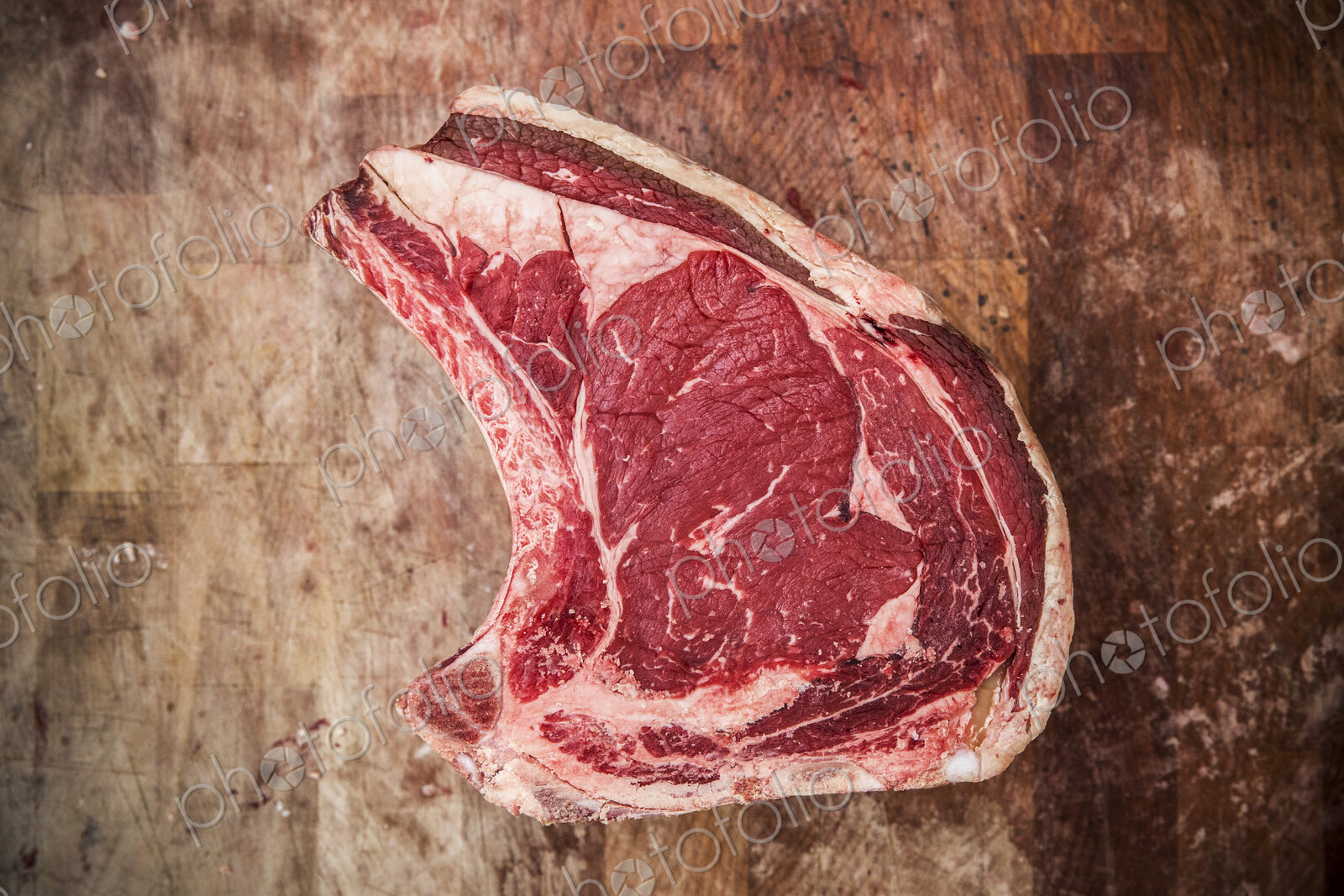 High angle close up of a beef forerib on a wooden butcher’s block.
