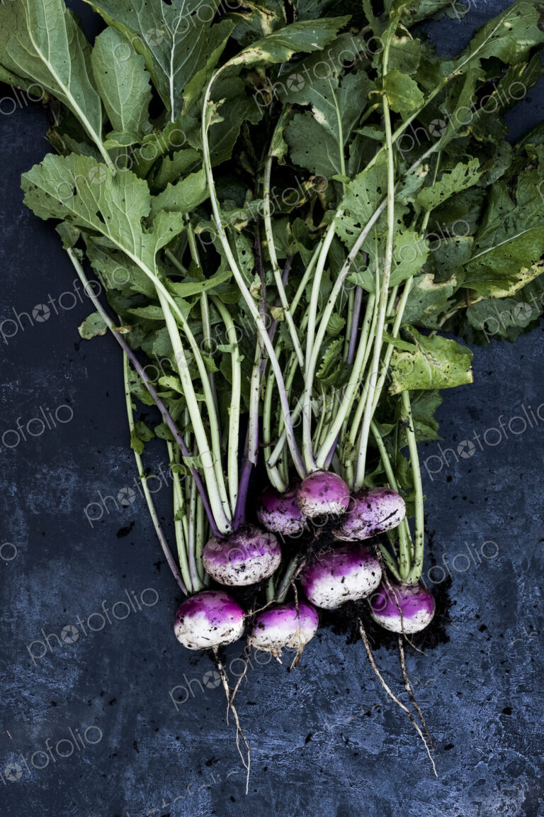 High angle close up of a bunch of freshly picked pink turnips on grey background.