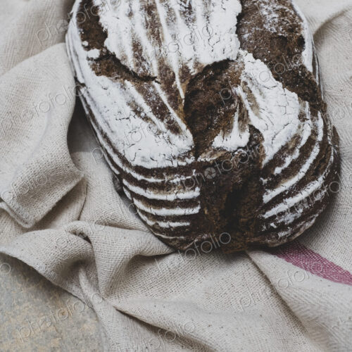 High angle close up of a freshly baked loaf of brown bread on tea towel. High angle close up of a freshly baked loaf of brown bread on tea towel.