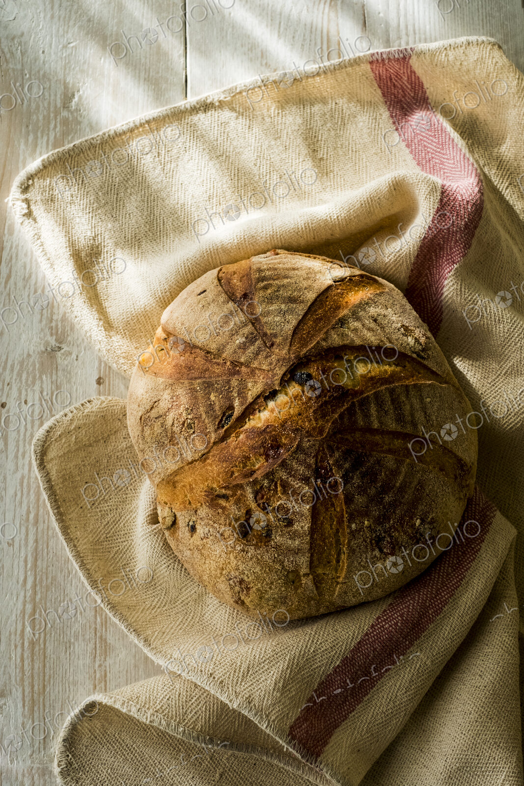 High angle close up of a freshly baked round loaf of bread on tea towel.
