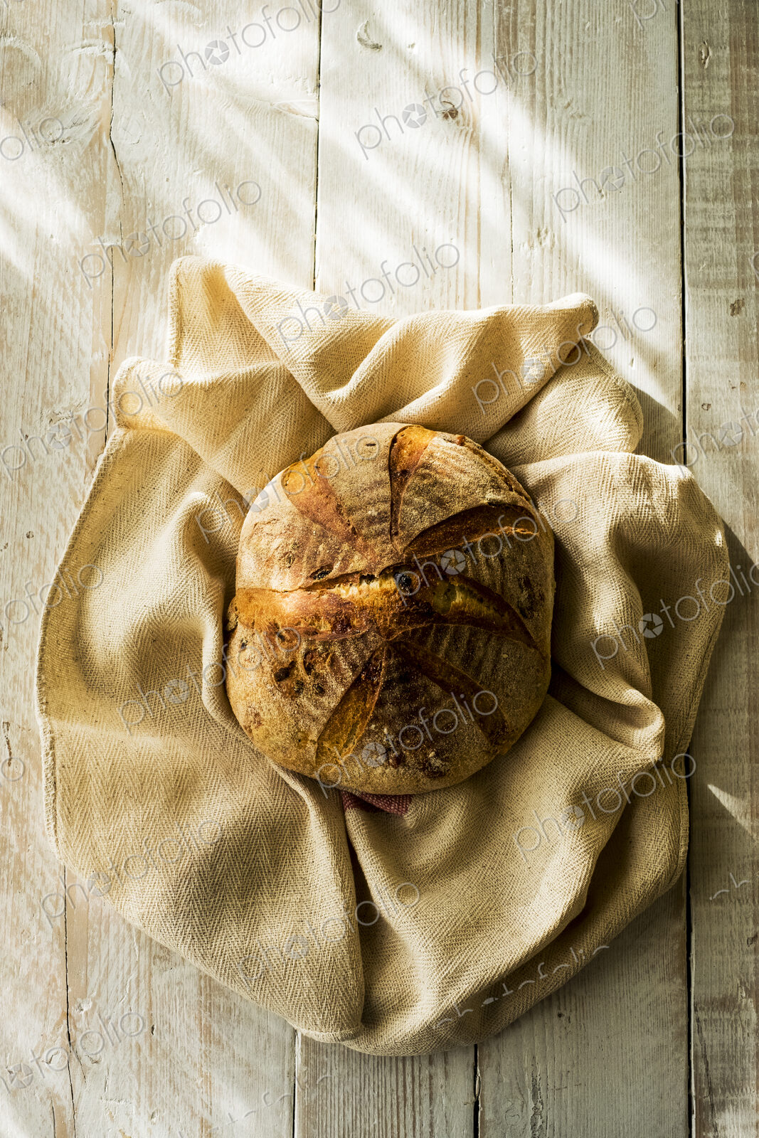 High angle close up of a freshly baked round loaf of bread on tea towel.