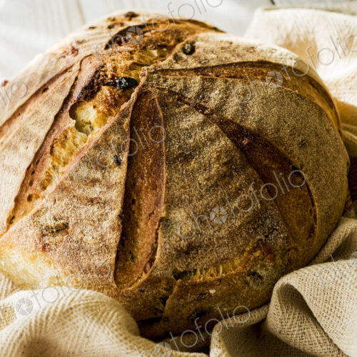 High angle close up of a freshly baked round loaf of bread on tea towel. High angle close up of a freshly baked round loaf of bread on tea towel.